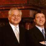 Two men standing side by side smiling.